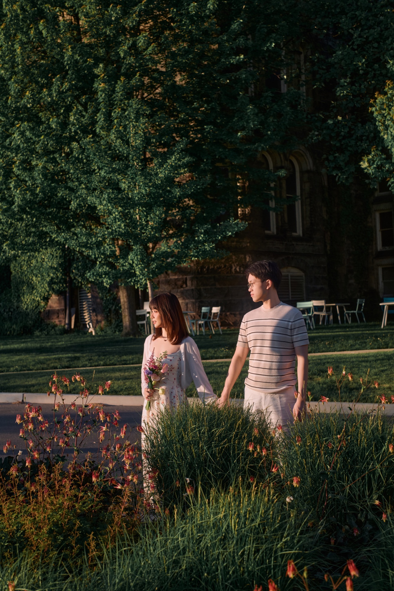 A couple in late afternoon light beside a garden