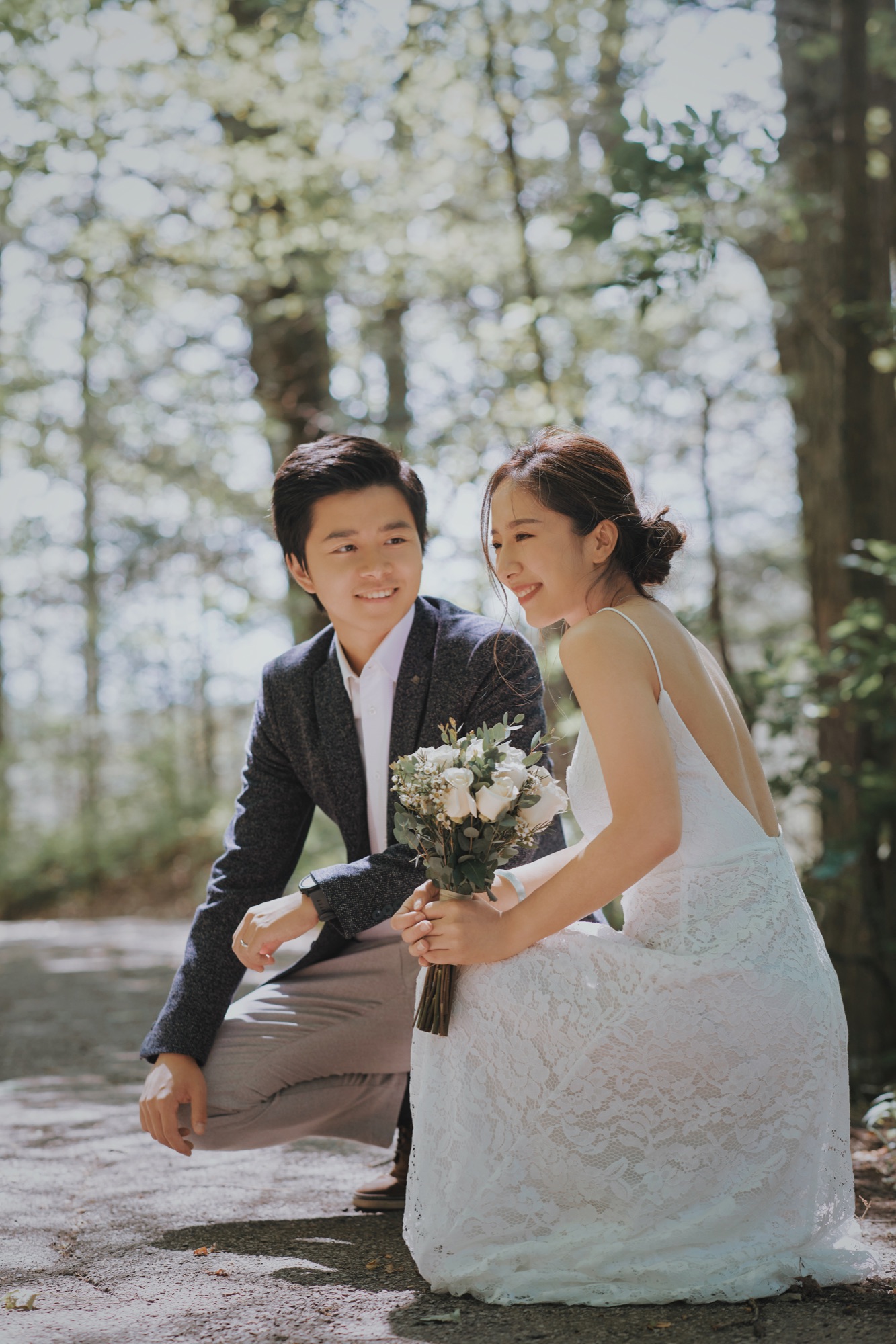 A couple smiling in soft woodland light