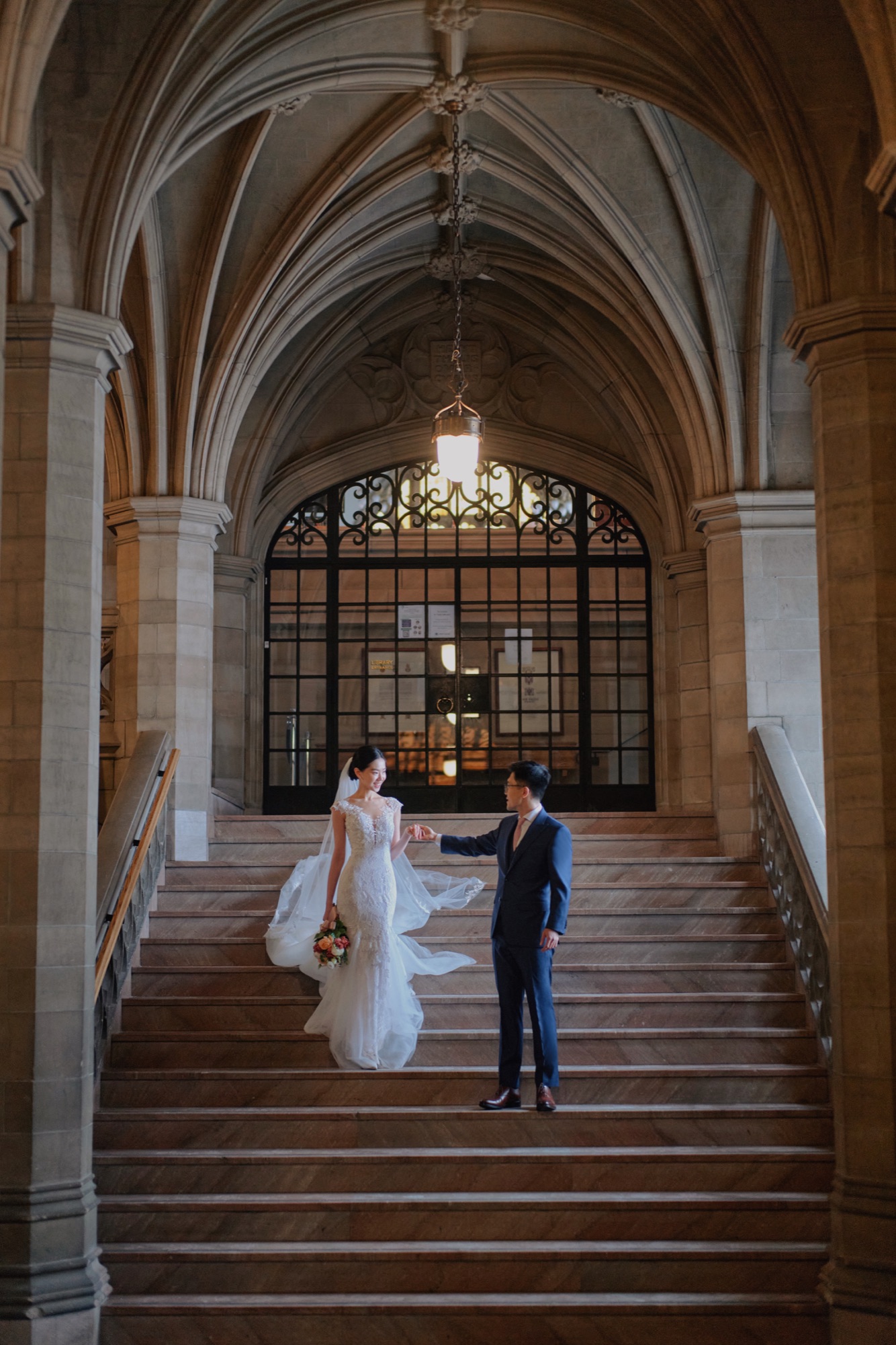 Newlyweds holding hands on a grand staircase